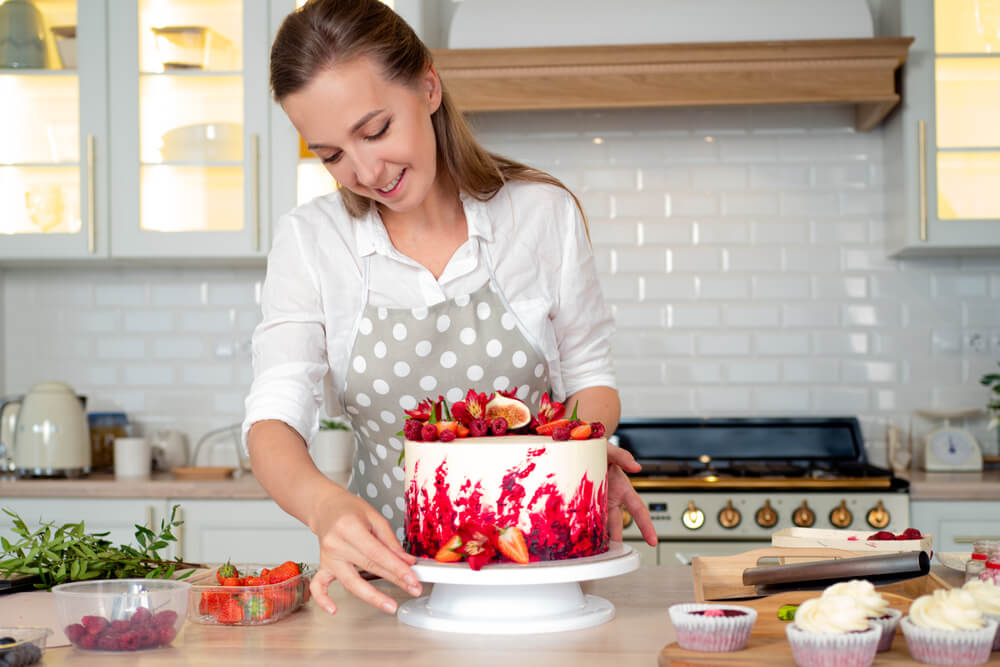 Confeiteira decorando bolo com frutas vermelhas